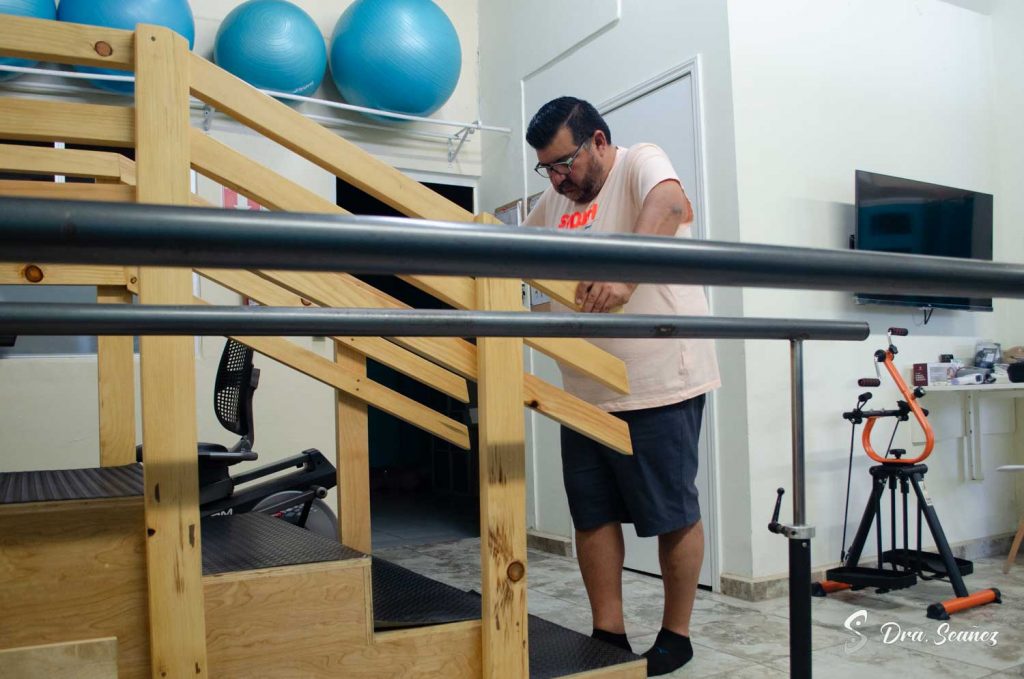 Hombre en rehabilitación utilizando una rampa para reeducación de la marcha en centro de fisioterapia.